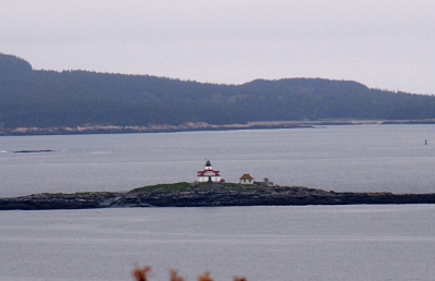 [White and red, three story structure on an island in the harbor.]